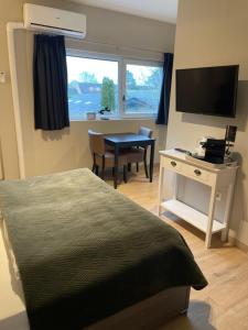 a bedroom with a bed and a desk and a television at De Stadspoort appartementen in Aardenburg