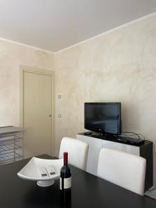 sala de estar con mesa, TV y 2 sillas blancas en Benaco Village Home, en Toscolano Maderno