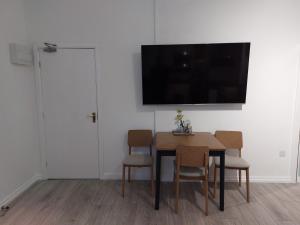 een eetkamer met een tafel en stoelen en een televisie bij Flat 6 Corner House in Doncaster