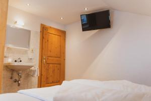 a bedroom with a bed and a sink and a television on the wall at Gästehaus Annemarie in Kauns