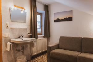 ein Badezimmer mit einem Sofa, einem Waschbecken und einem Stuhl in der Unterkunft Gästehaus Annemarie in Kauns