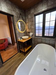 a bathroom with a tub and a round mirror at Berkri Gastro Yard & Guest House in Yenokavan