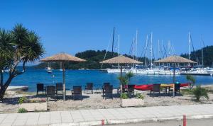 eine Gruppe von Stühlen und Sonnenschirmen am Strand mit Booten in der Unterkunft Oscar Hotel Lefkada in Nydri