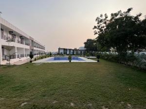 a large yard with a swimming pool in front of a building at Inara Farms in Lucknow