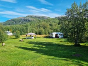 a field with a tent and a table in the grass at Caravan at the Cottage House in Ertenvåg