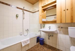 a bathroom with a sink and a shower and a tub at Alpina Holiday Living Zirbenstrasse in Obertauern