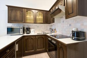 オーバータウエルンにあるAlpina Holiday Living Zirbenstrasseのキッチン(木製キャビネット、シンク、電子レンジ付)