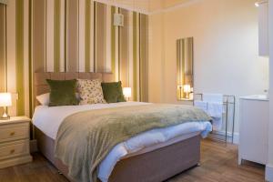 a bedroom with a large bed with green and white stripes at Cranmere Lichfield in Lichfield