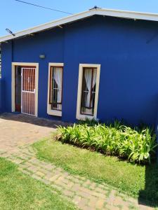 un bâtiment bleu avec des fenêtres et des plantes devant lui dans l'établissement BellaMaria, à Pretoria