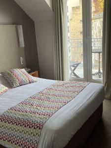 a bed in a hotel room with a window at Campanile Paris 14 - Maine Montparnasse in Paris