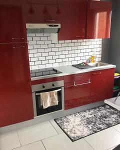 a kitchen with red cabinets and a stove and a sink at Appt 56m2 en plein centre ville et mer a 200m in Berck-sur-Mer