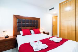 Un dormitorio con una gran cama blanca con almohadas rojas. en tuGuest Avenida de la Investigación - Free parking, en Granada