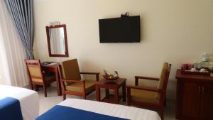 a room with a bed and chairs and a television at Navy Hotel Cam Ranh in Cam Ranh