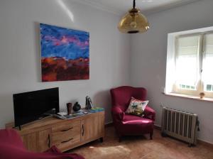 a living room with a tv and a red chair at Casa Loli-Villar in Luarca