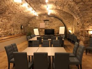une salle de conférence avec des tables et des chaises dans un mur en pierre dans l'établissement La Bastide de Sanilhac, à Sanilhac
