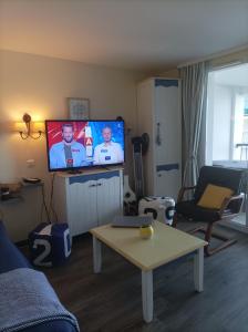 uma sala de estar com uma televisão com dois homens no ecrã em Appartement face Mer em Tréboul