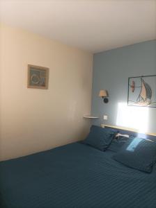 um quarto com uma cama com um edredão azul em Appartement face Mer em Tréboul