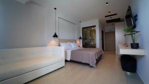 une chambre d'hôtel avec un lit blanc et un canapé dans l'établissement Enjoy Lichnos Bay Village, Camping, Hotel and Apartments, à Parga