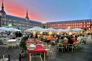 een groep mensen die aan tafels voor een gebouw zitten bij Woohoo Rooms Boutique Luna in Madrid