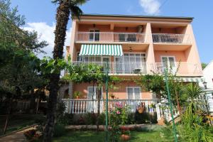 una casa rosa con balcones y flores en el patio en Apartmani Roje Sveti Filip I Jakov, en Sveti Filip i Jakov