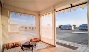 Habitación con ventana grande y mesa. en The Heritage Luxurious Camp en Jaisalmer
