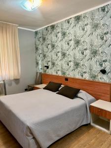 a bedroom with a bed and a wall with a floral wallpaper at Hotel Delle Rose in Mestre