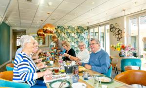 un gruppo di persone seduti a un tavolo in un ristorante di De Maasparel Nextdoor Suites ad Arcen