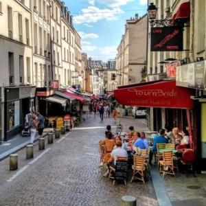 een groep mensen die aan tafel zitten in een stadsstraat bij Charmant appartement de 38m² -Quartier Latin in Parijs