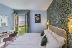 a bedroom with a bed and a desk and a window at Hotel Villa Lubrense Sorrento in Massa Lubrense