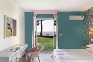 a bedroom with a bed and a desk and a window at Hotel Villa Lubrense Sorrento in Massa Lubrense