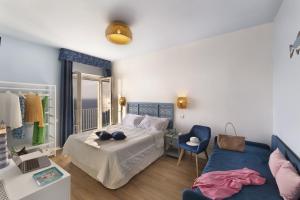 a bedroom with a bed and a blue couch at Hotel Villa Lubrense Sorrento in Massa Lubrense