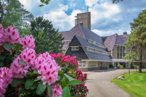 ein Gebäude mit rosa Blumen davor in der Unterkunft Hotel Woudschoten in Zeist