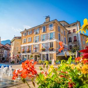 un grand bâtiment avec des fleurs devant lui dans l'établissement Évasion Hébergement, à Allevard