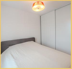 - une chambre avec un lit blanc et une lampe dans l'établissement Appartement T2 Moderne St Julien, à Saint-Julien-en-Genevois