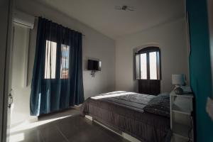 1 dormitorio con 1 cama con cortinas azules y ventana en Casa Vacanze - Il Balconcino sul Castello, en Iglesias