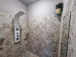 a bathroom with a shower with tiles on the wall at VintageCo. Apartments in Motta SantʼAnastasia