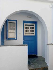 een blauwe deur in een witte muur met een raam bij Cozy Studio in Beautiful Apollonas Beach Naxos in Apollon