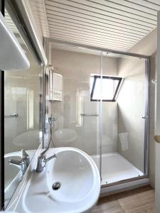 y baño blanco con lavabo y ducha. en Residencial Moderna, en Torres Vedras