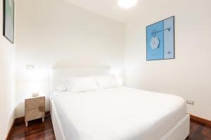 een witte slaapkamer met een bed en een nachtkastje bij Bicocca Terrace Two Bedroom Apartment -Top Collection in Milaan