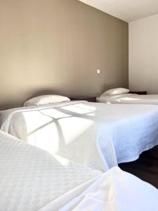 Residencial Moderna في توريس فيدراس: سريرين في غرفة ذات أغطية بيضاء