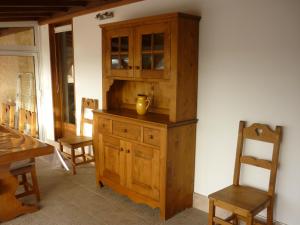 a wooden cabinet and a chair in a room at Villa du soleil levant in Apt