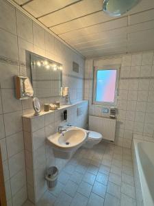 a bathroom with a sink and a toilet and a tub at Hotel Harbauer in Schwarzenbruck