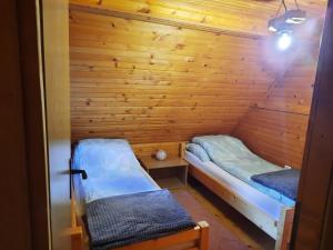 a small room with two beds in a wooden wall at Vikendica Rajvosa Vlašić in Šišava