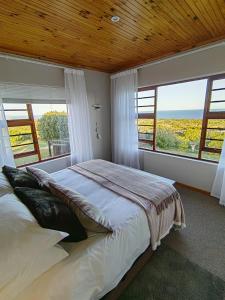 a bedroom with a large bed and large windows at The Nightingale in Groot Brak Rivier