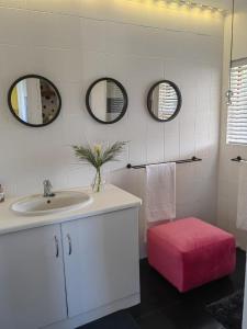 a bathroom with a sink and a pink ottoman at The Nightingale in Groot Brak Rivier