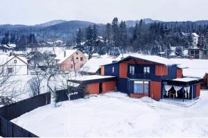 a house is covered in snow in a town at MiShelter in Migovo
