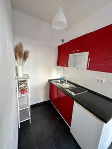 a small kitchen with red cabinets and a sink at Apartment in zentraler Lage (mit Arbeitsecke) in Krefeld