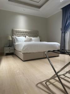 a white bedroom with a bed and a glass table at GAZLA in Riyadh