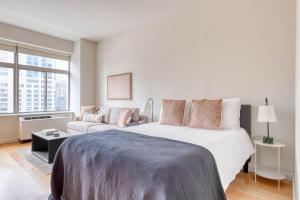 a white bedroom with a large bed and a couch at FiDi studio w gym doorman nr Freedom Tower NYC-1097 in New York