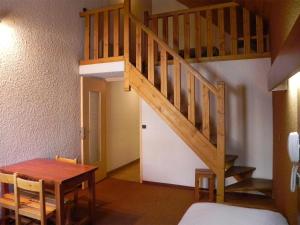 Cette chambre dispose d'un escalier en bois et d'une table. dans l'établissement Hôtel Résidence Les Colchiques, au Monêtier-les-Bains